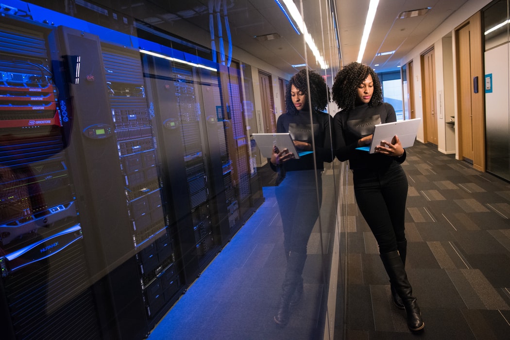 woman holding a laptop infront of a server room