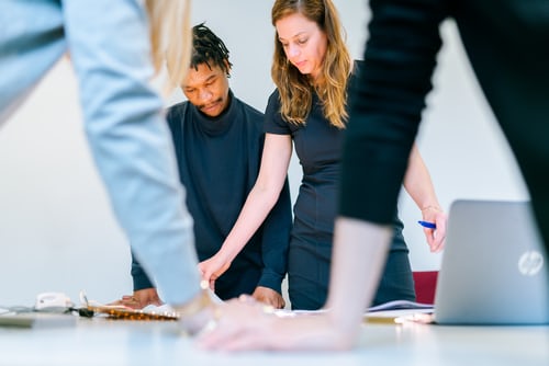 a group of people working around a table, looking down