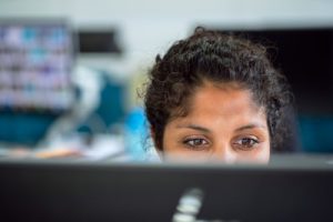 woman working behind a monitor, only can see her eyes